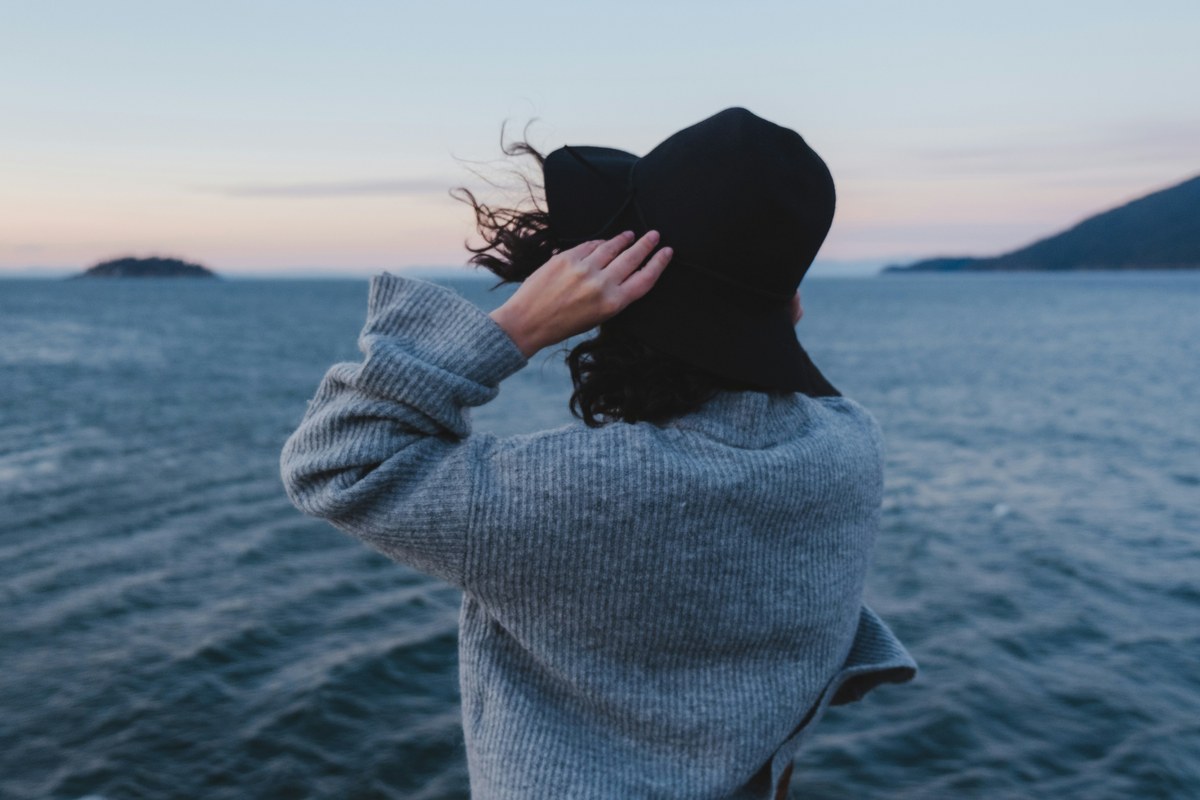 A woman standing at the sea's edge, looking out to the horizon
